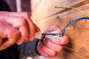 Hands working on an electrical outlet during a home electrical service